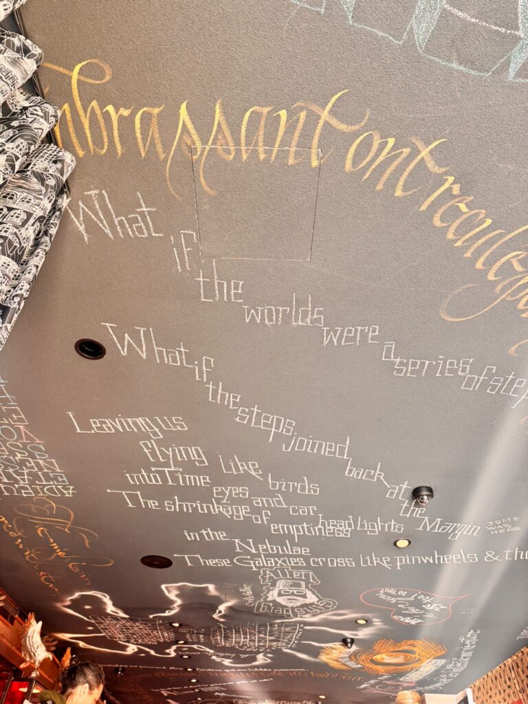 Plafond du Mama Shelter Paris East avec des phrases poétiques écrites à la craie blanche et des inscriptions dorées, accompagnées de dessins.